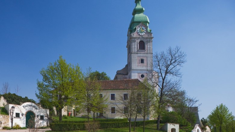Church in Unterretzbach with green tower and surrounding buildings.