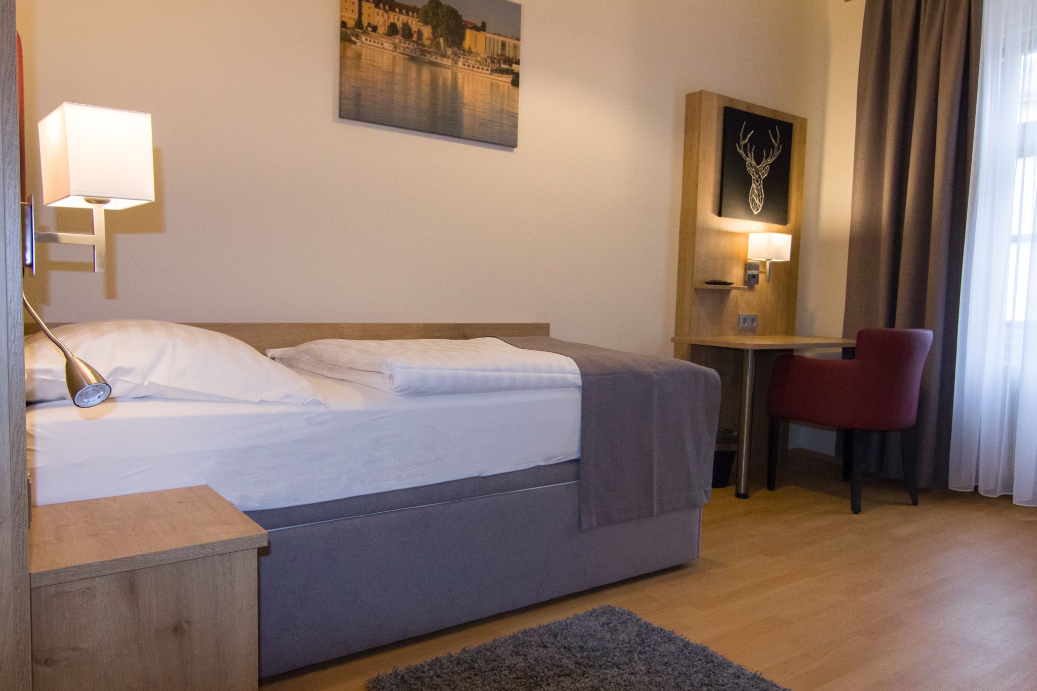 Single room with bed, desk and red chair.