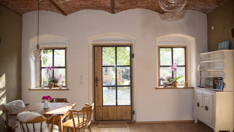 Bright dining area with two windows and wooden/glass door