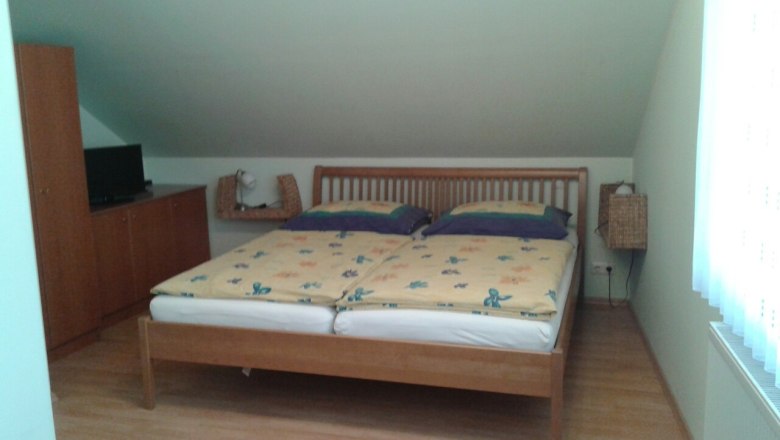 A bedroom with a double bed, a wardrobe and a TV on a cupboard.