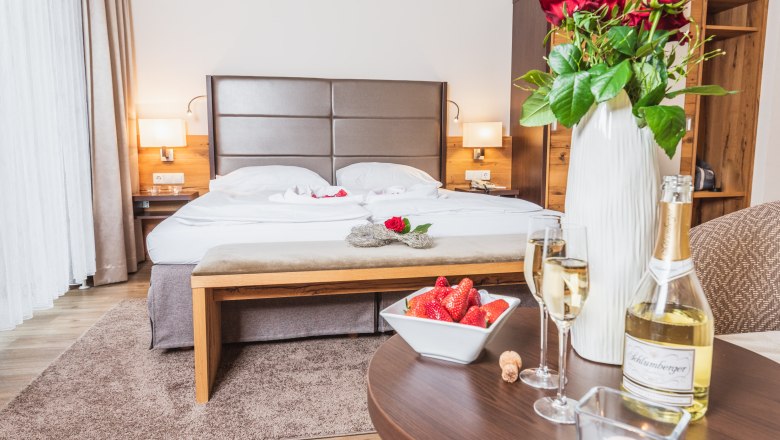 Double room at Hotel Schneeberghof with bed, roses, sparkling wine and strawberries.