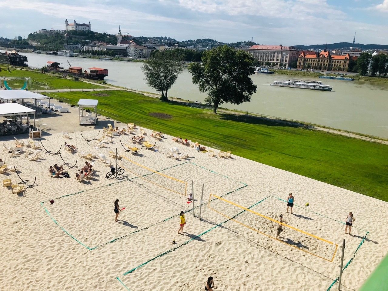 Danube near Bratislava, Danube bank with sand, deckchairs and people playing ball.