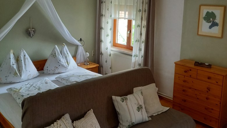 Cozy guest room with double bed, sofa and wooden furniture.