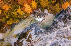 Die bunten Blätter der Bäume spiegeln die goldene Herbstsonne wider und schaffen eine malerische Kulisse für den klaren, plätschernden Bach, der durch die Schlucht fließt. Wanderer können die frische, klare Luft genießen und die beeindruckenden Felsformationen bewundern, die diesen Naturpark zu einem wahren Paradies der Blicke machen.