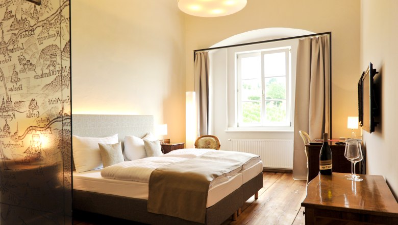 Elegant hotel room with double bed, wooden floor and large window.