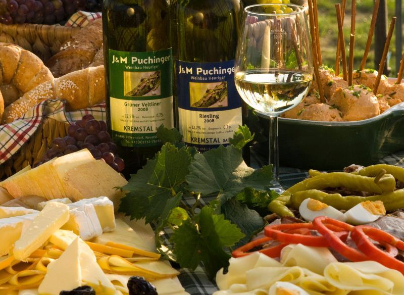 Heurigen snack with wine, cheese, bread and cold cuts on a table.