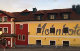 Facade of the Bergwirt Schrammel & Mohnhotel with red and yellow paint.