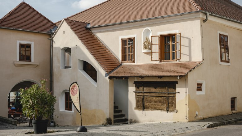 Historic building with red tiled roofs and open windows.