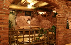 Rustic room with brick walls, wooden tables and decorations made from grapevines.