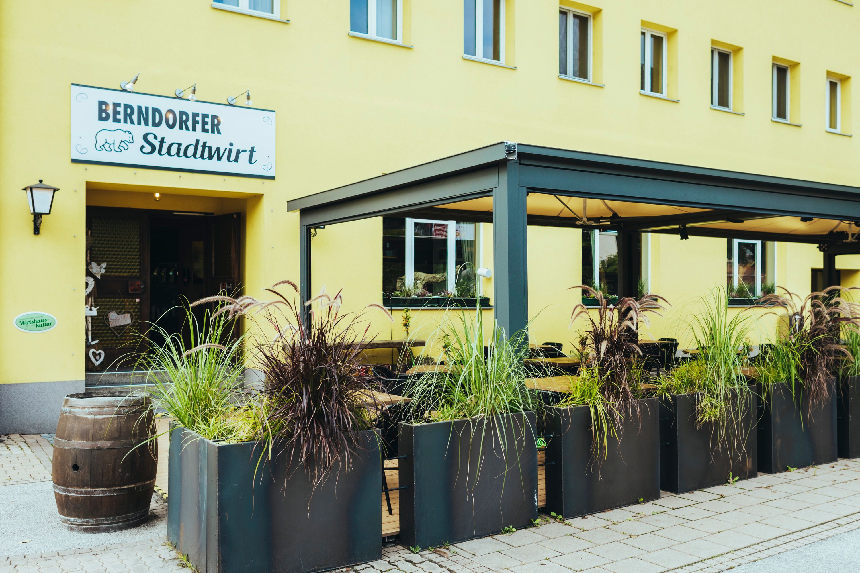 Entrance to the Berndorfer Stadtwirt with covered garden and plants.