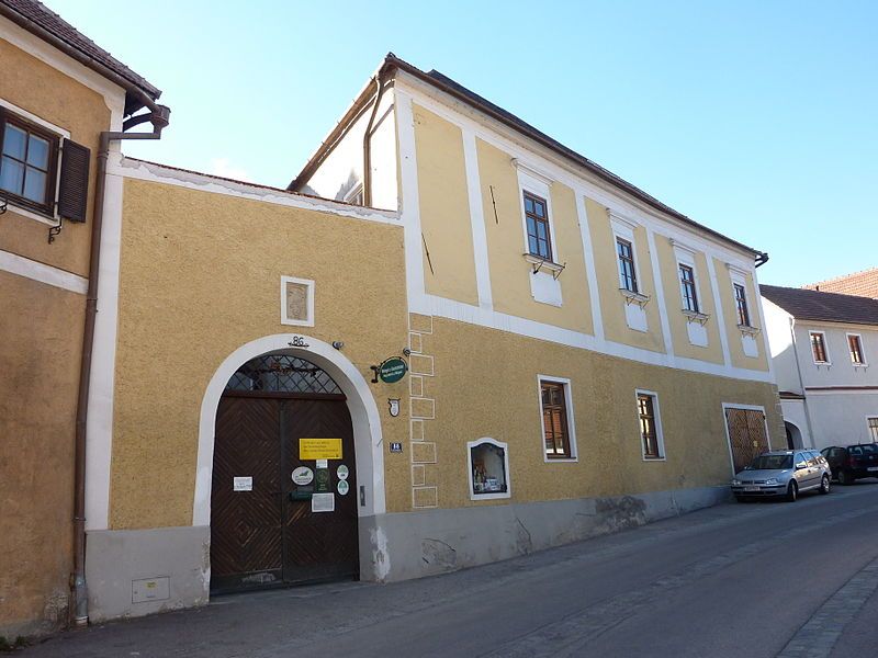 Yellow two-story building with wooden gate and windows in a street.
