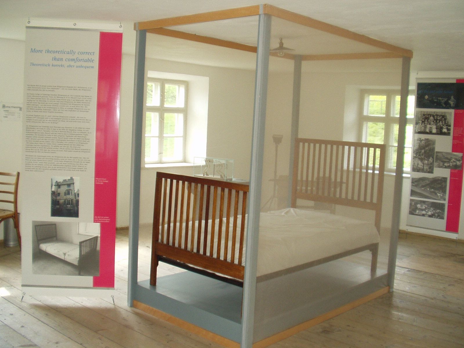 Exhibition room with a bed behind glass and information boards.