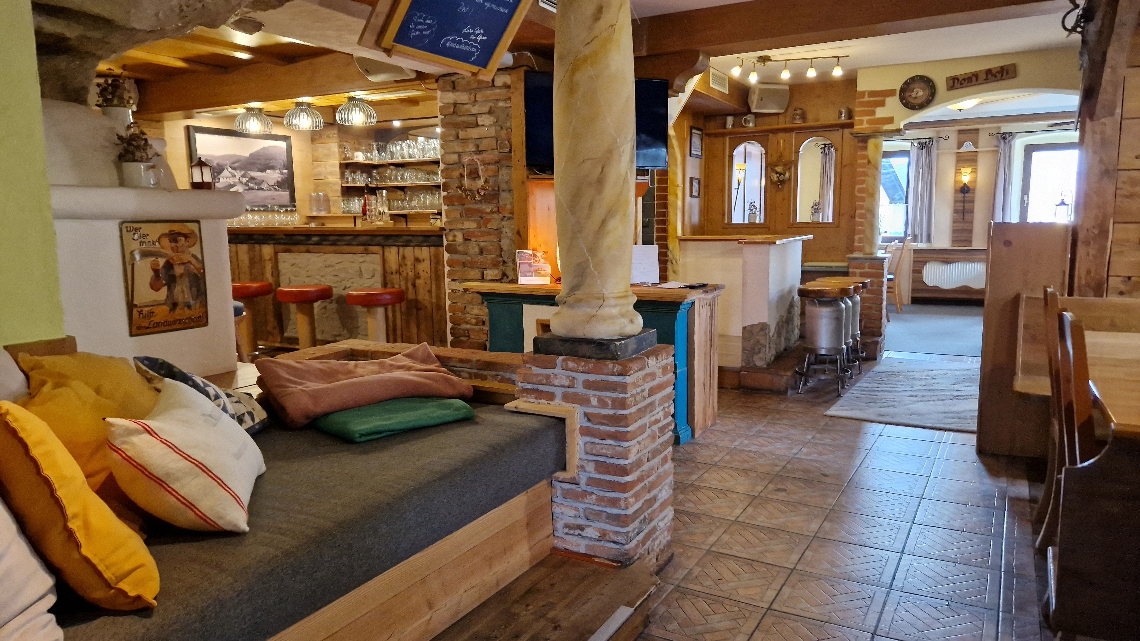 A lounge area with rustic decor, wooden furniture, and a bar with red stools.