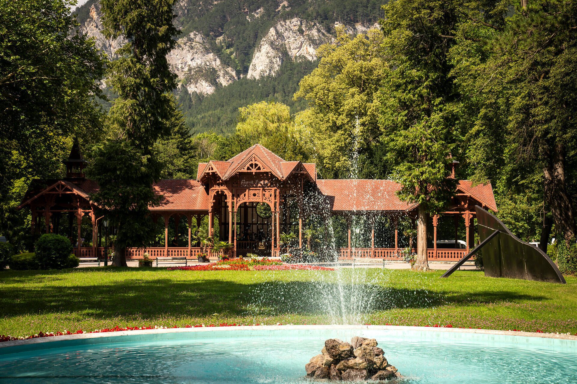 Surrounded by majestic mountains and lush greenery, the historic pavilion exudes an inviting atmosphere. The gentle sounds of water gushing from the fountain harmonize perfectly with the picturesque backdrop and invite you to enjoy the beauty of nature.
