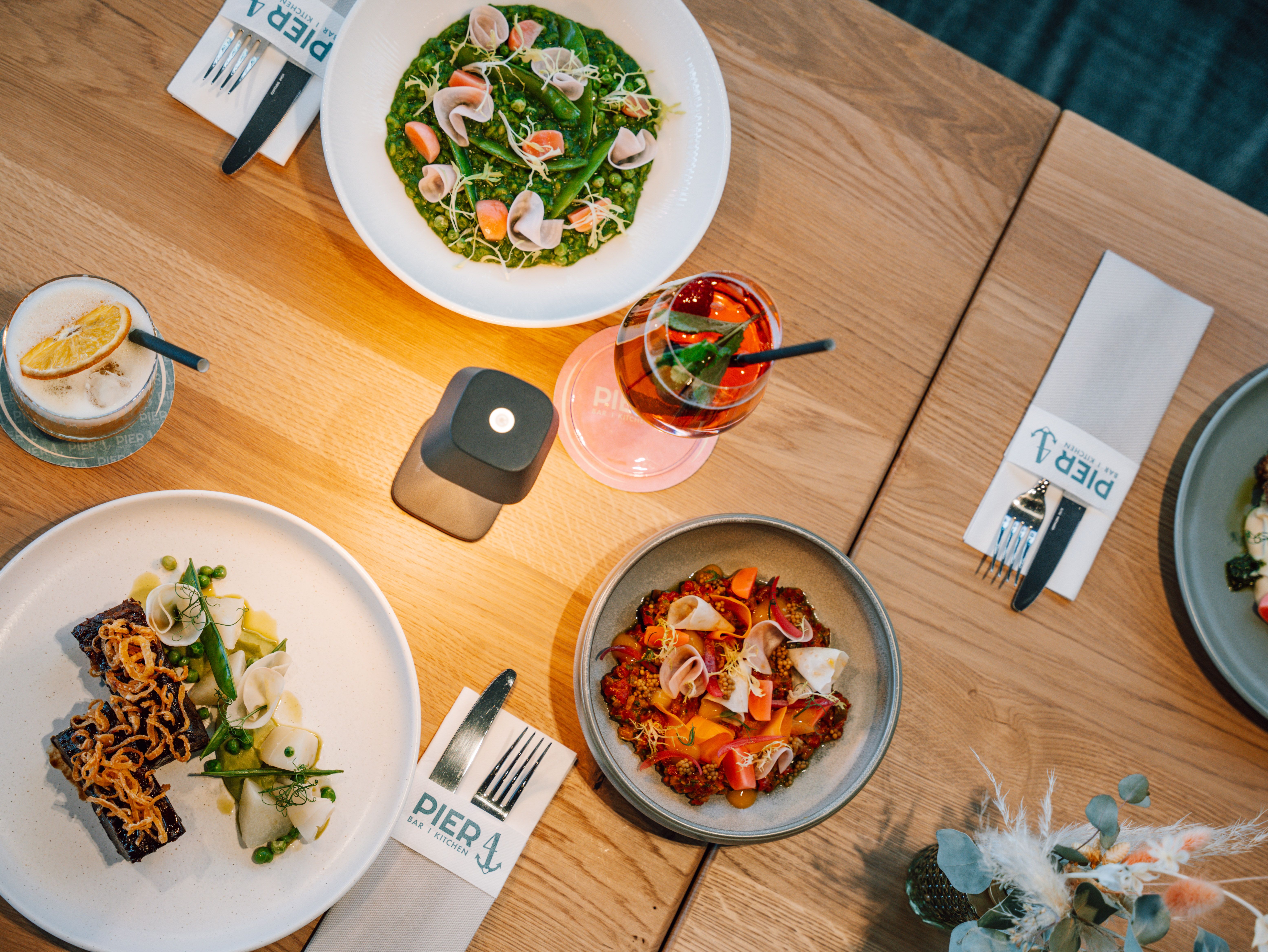Various dishes and drinks on a wooden table in the Pier 4 restaurant.