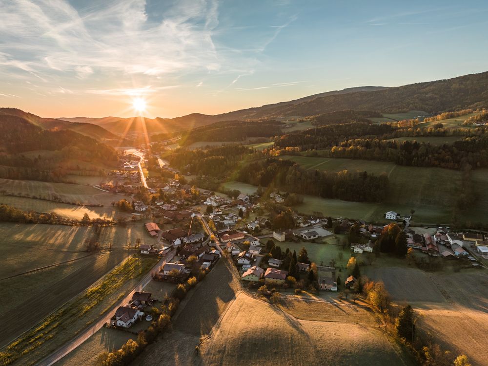 Aerial view of a village in a hilly landscape at sunset.