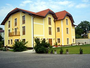 Yellow two-storey building with red roof and well-kept garden.