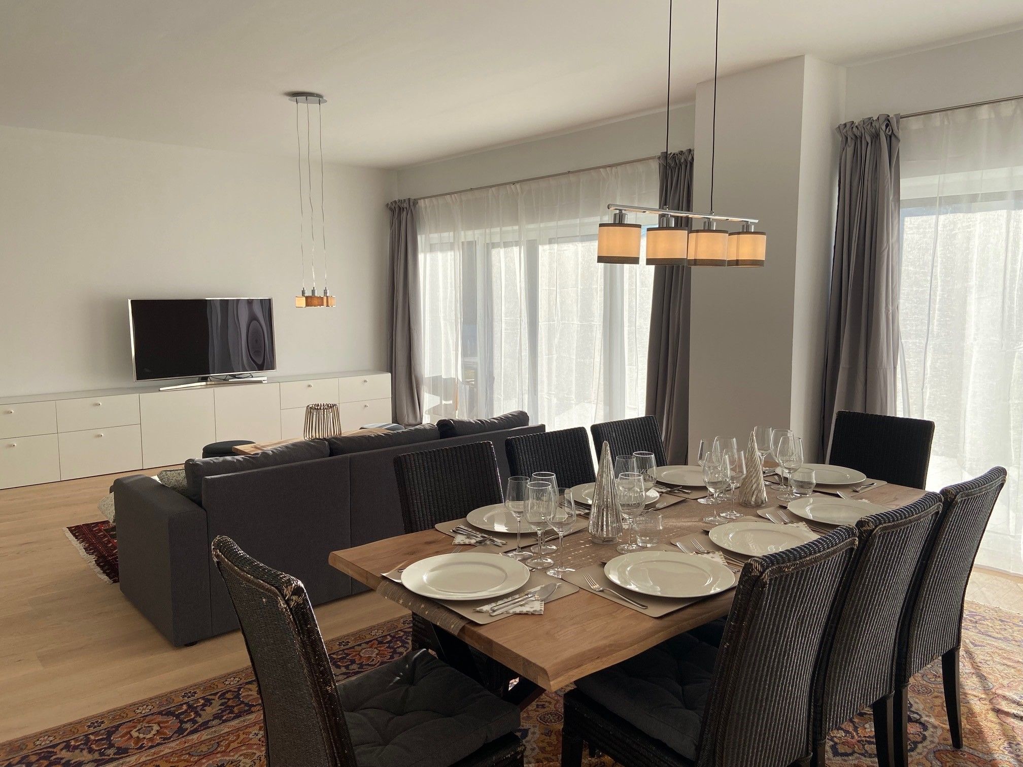 Modern living/dining area with dining table, chairs, sofa and TV.