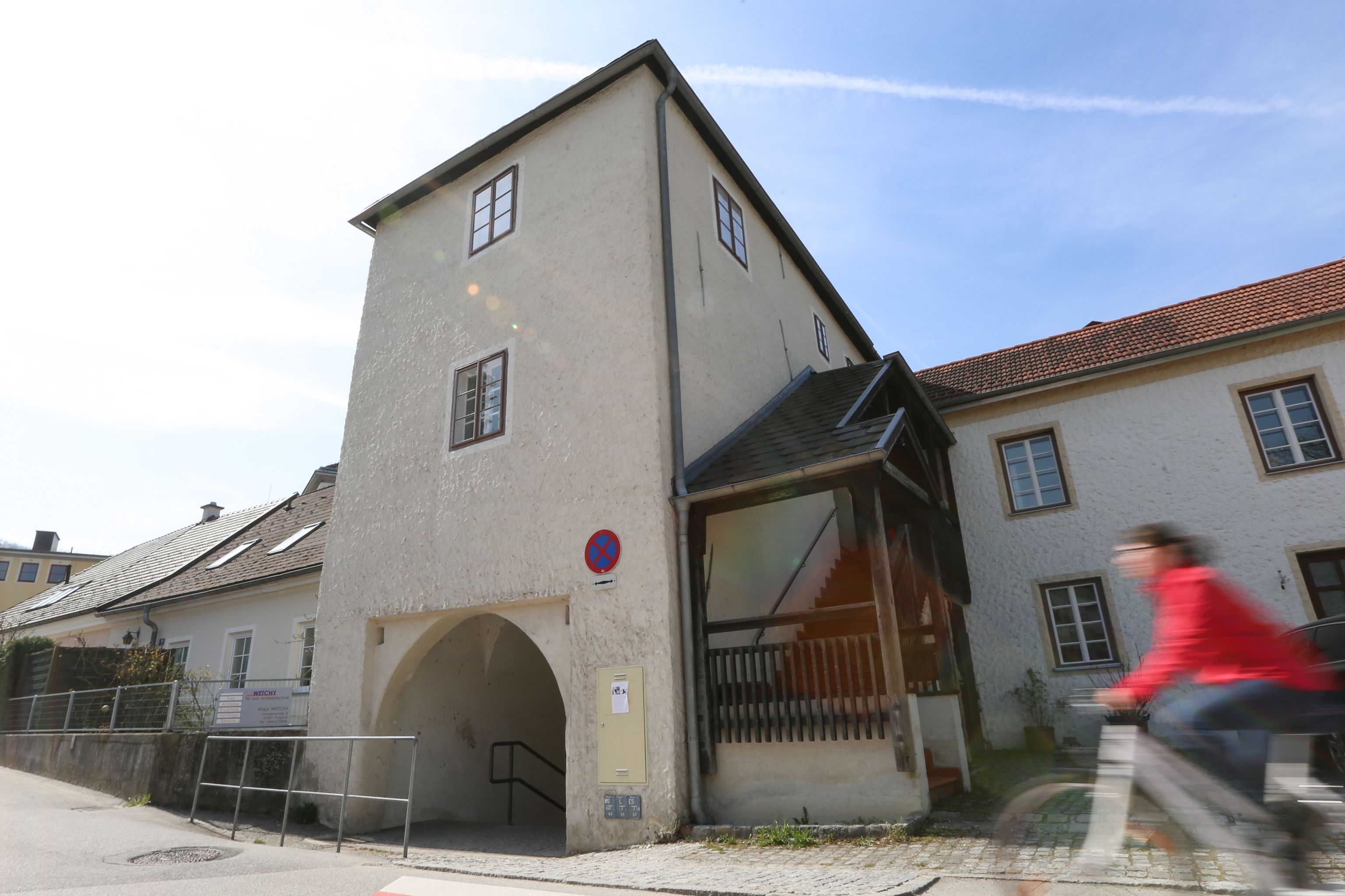 A historic building with an archway and a person on a bicycle in the foreground.