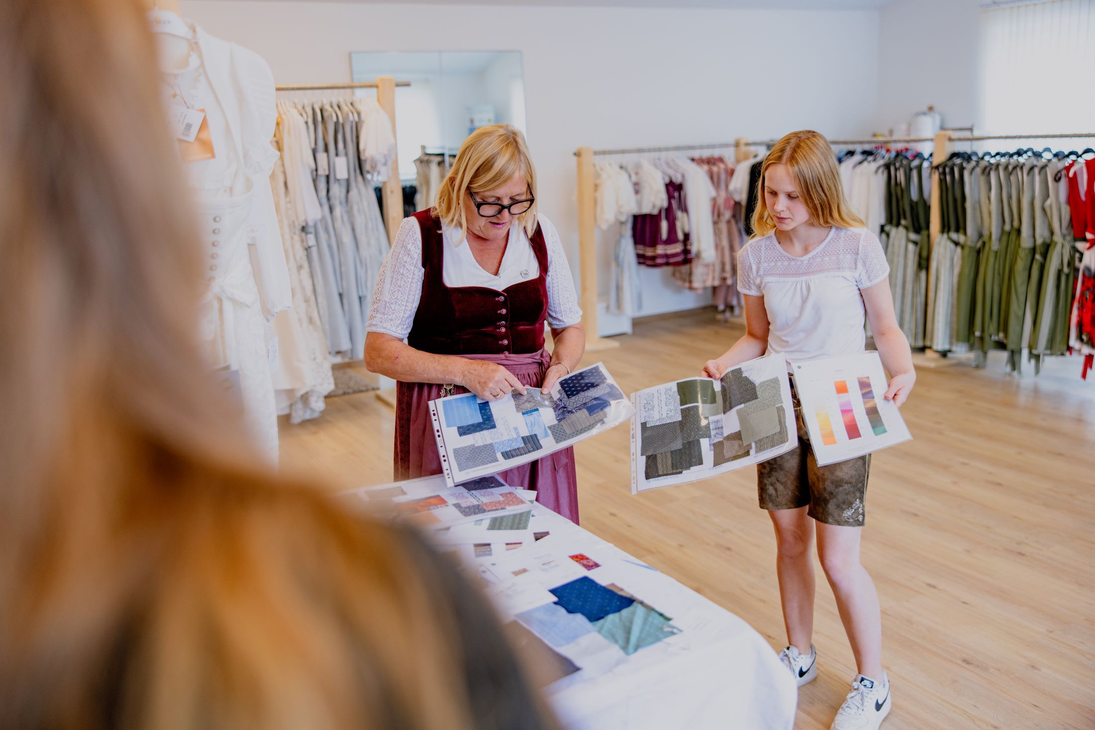 Two women looking at fabric samples in a traditional costume store.