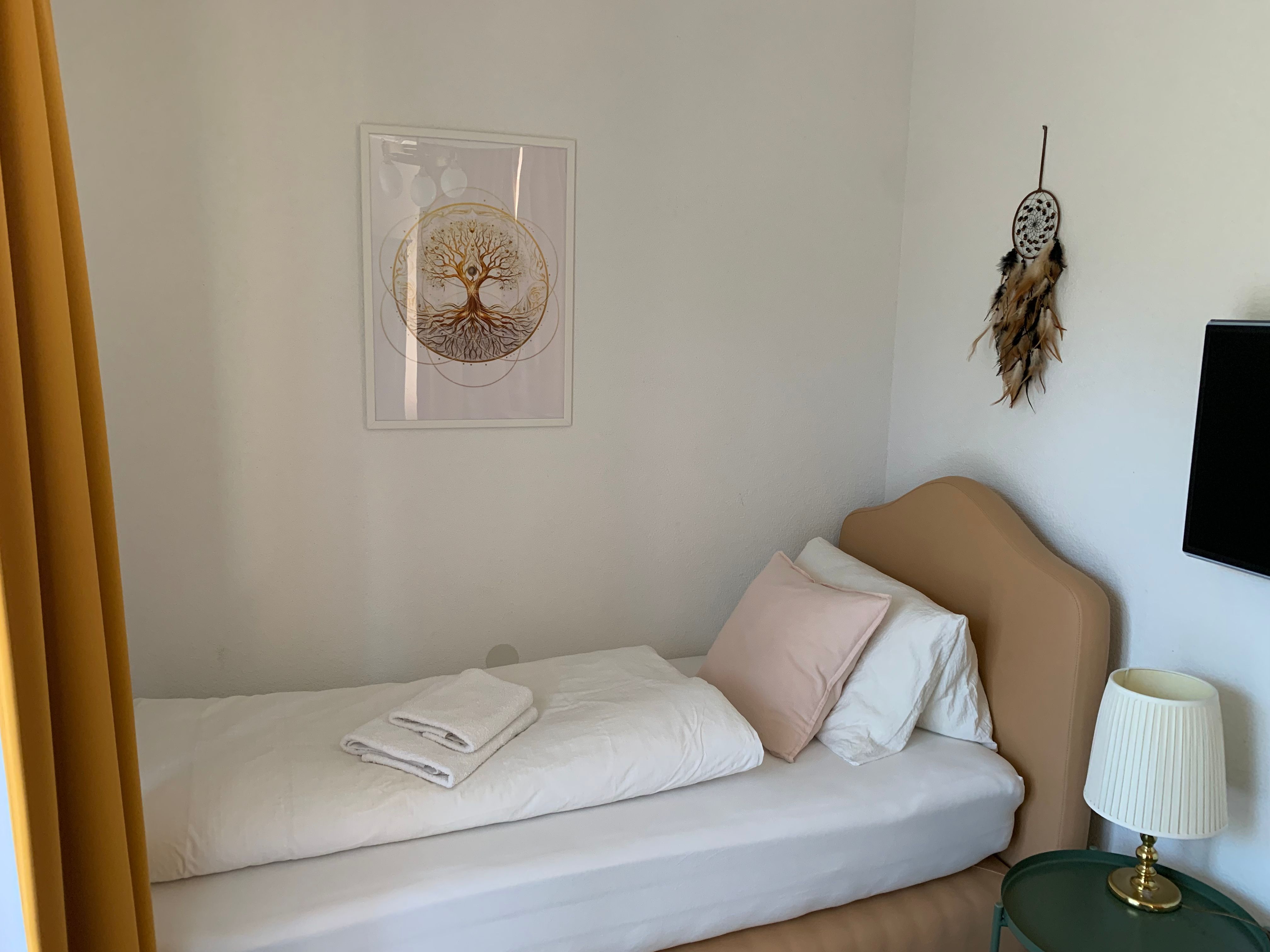 Single room with bed, dreamcatcher and lamp.