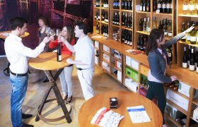 People in a wine store tasting wine and selecting bottles.