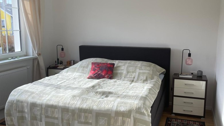 One bedroom with a double bed, two bedside tables and carpets on a wooden floor.