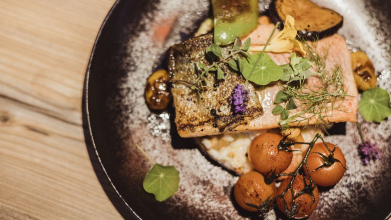 Salmon trout fillet on grammel risotto with vegetables and herbs on a plate.