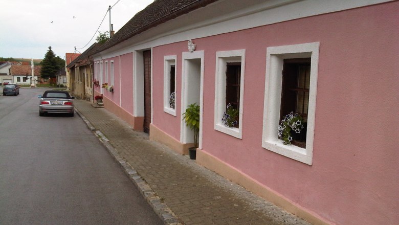 Street view with pink house and parked car.