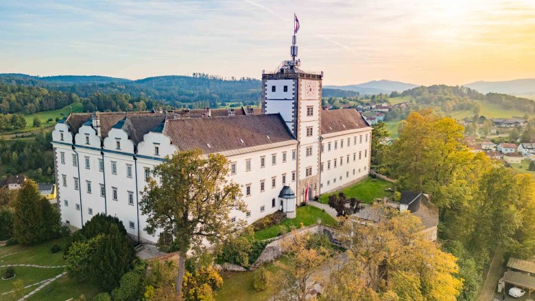 Aerial view of Weitra Castle in Austria at sunset, surrounded by green landscape and trees.