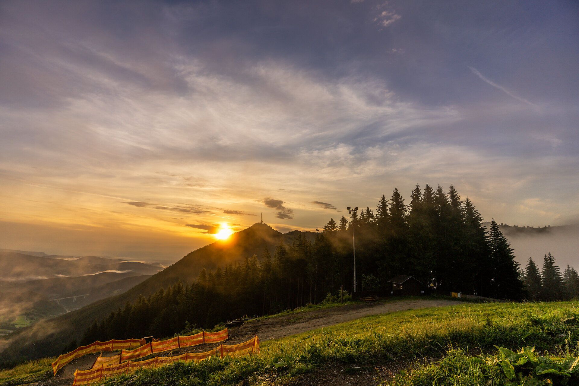 A breathtaking sunrise bathes the majestic mountains in golden light and gives the surrounding forests a mysterious glow. The fresh morning air and the gentle chirping of birds invite you to enjoy an unforgettable hike as nature awakens in all its glory.