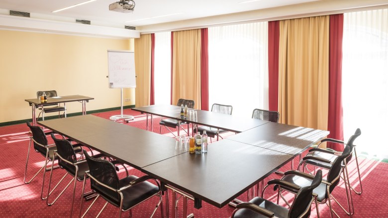 Conference room with U-shaped table, chairs, flipchart and projector.