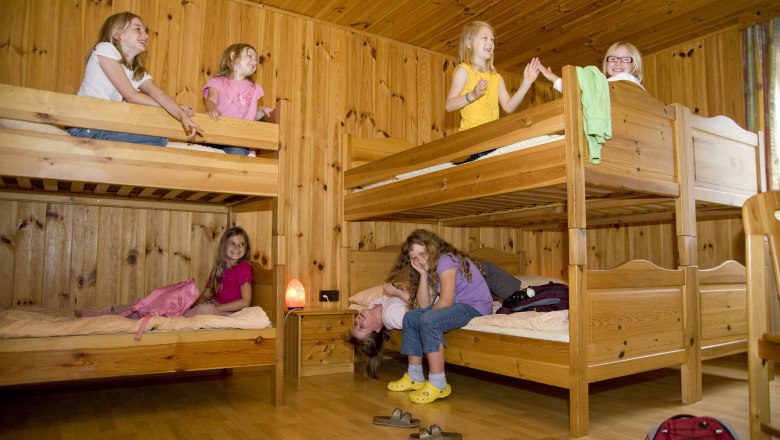 Children play in a room with wooden bunk beds.