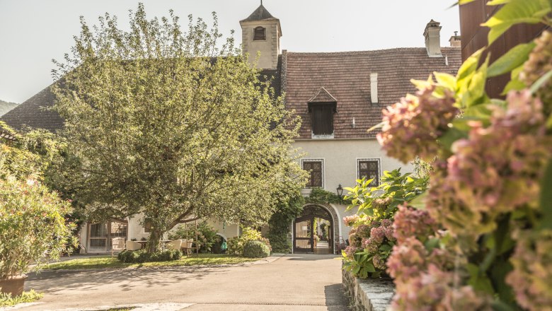 Inner courtyard of the Holzapfel winery with flowering plants and an old building in the background.