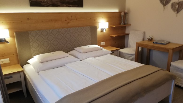 Cozy hotel room with double bed, wooden furniture and wall decoration.