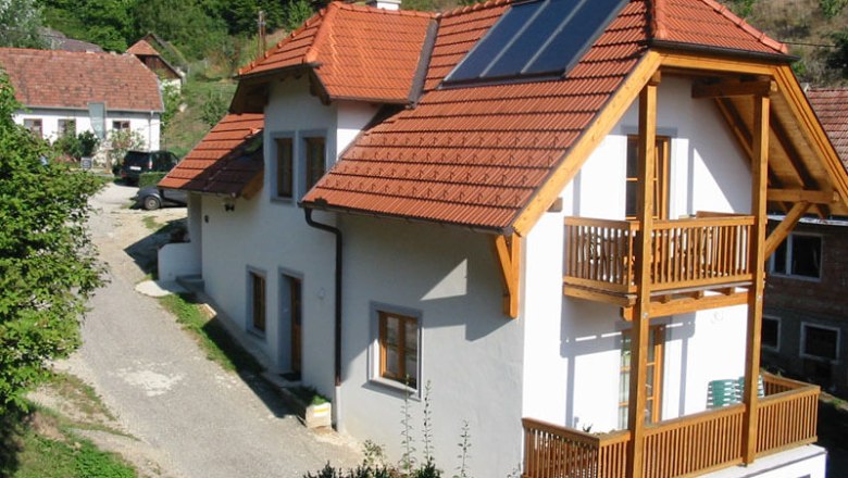 Vacation apartment with red roof and solar panels in a rural setting.
