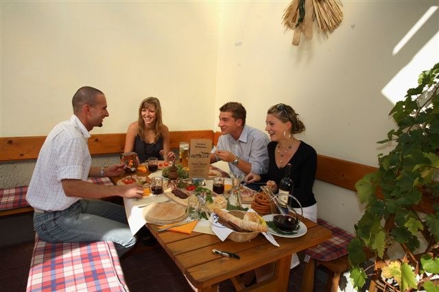 Four people sit at a table in a cozy courtyard and enjoy a meal.