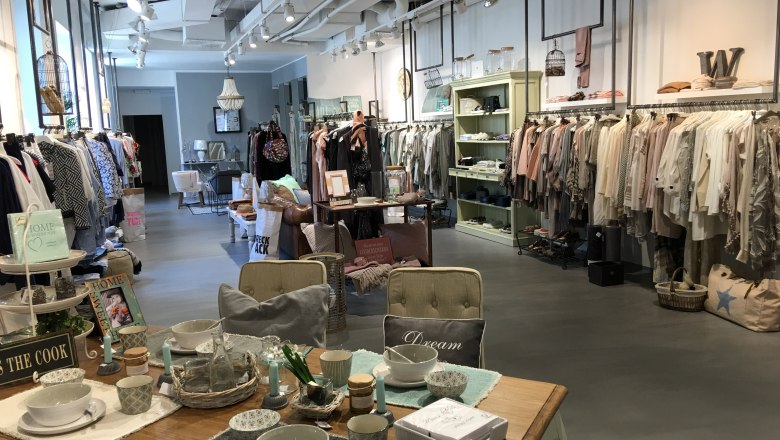 Interior view of a stylish clothing store with clothing and decorative items.