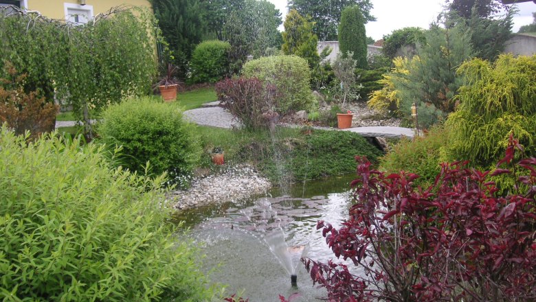 A well-tended garden with a pond, fountain and lush vegetation.