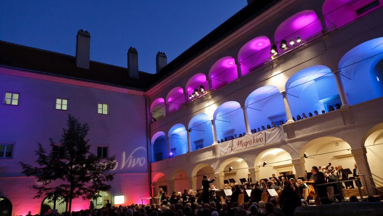 Concert in the arcade courtyard of the Kunsthaus Horn at night with colorful lighting.