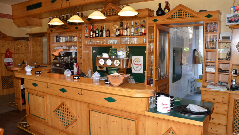 Interior view of a rustic bar with wooden furniture and drinks.
