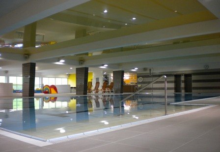 Interior view of an indoor pool with swimming pool and sun loungers.