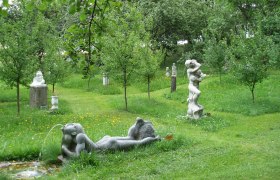 Sculptures in a green garden with trees.