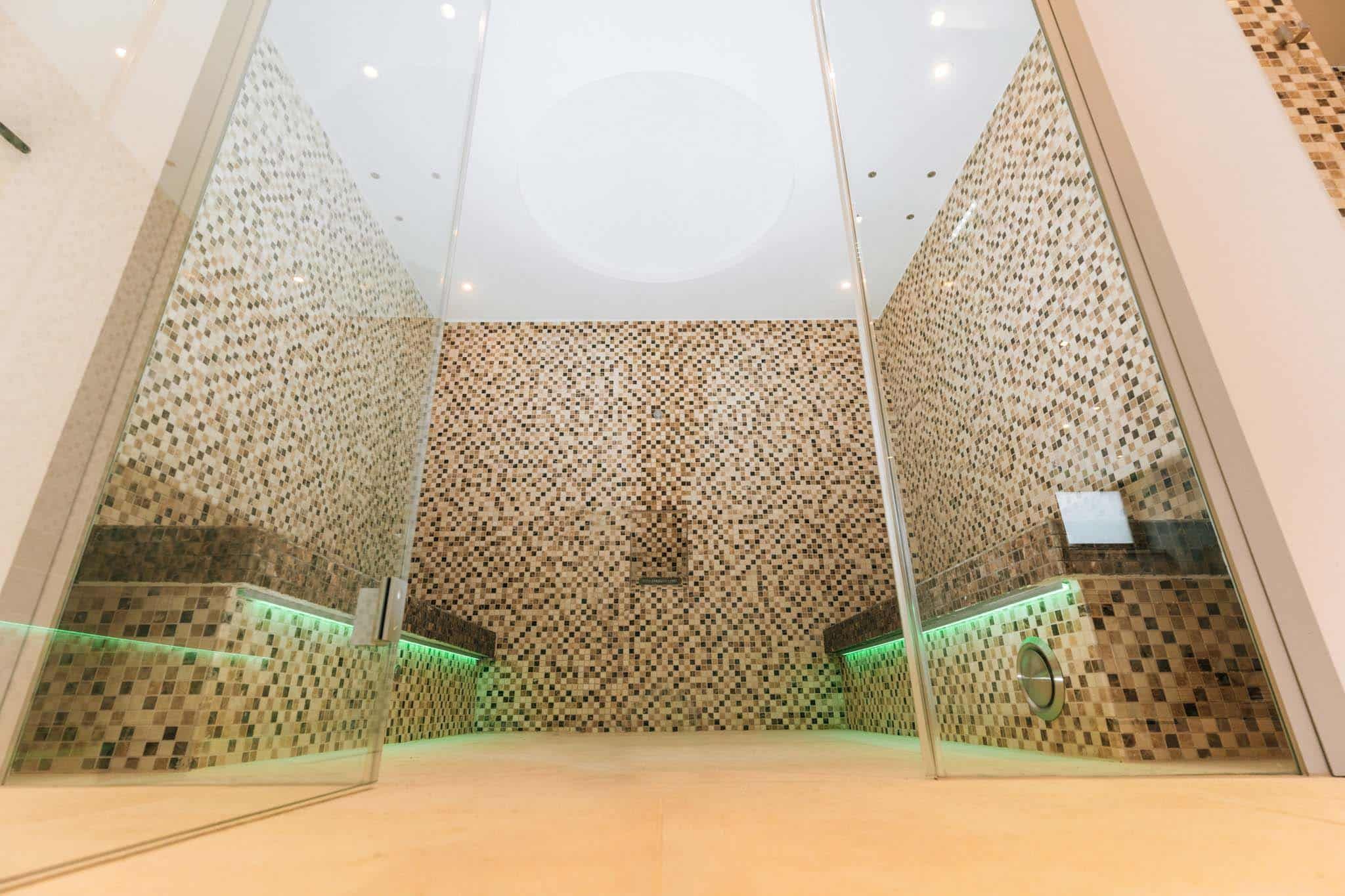 Modern sauna area with mosaic tiles and glass walls.