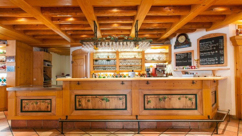 Rustic bar with wooden elements and wine glasses on the ceiling.