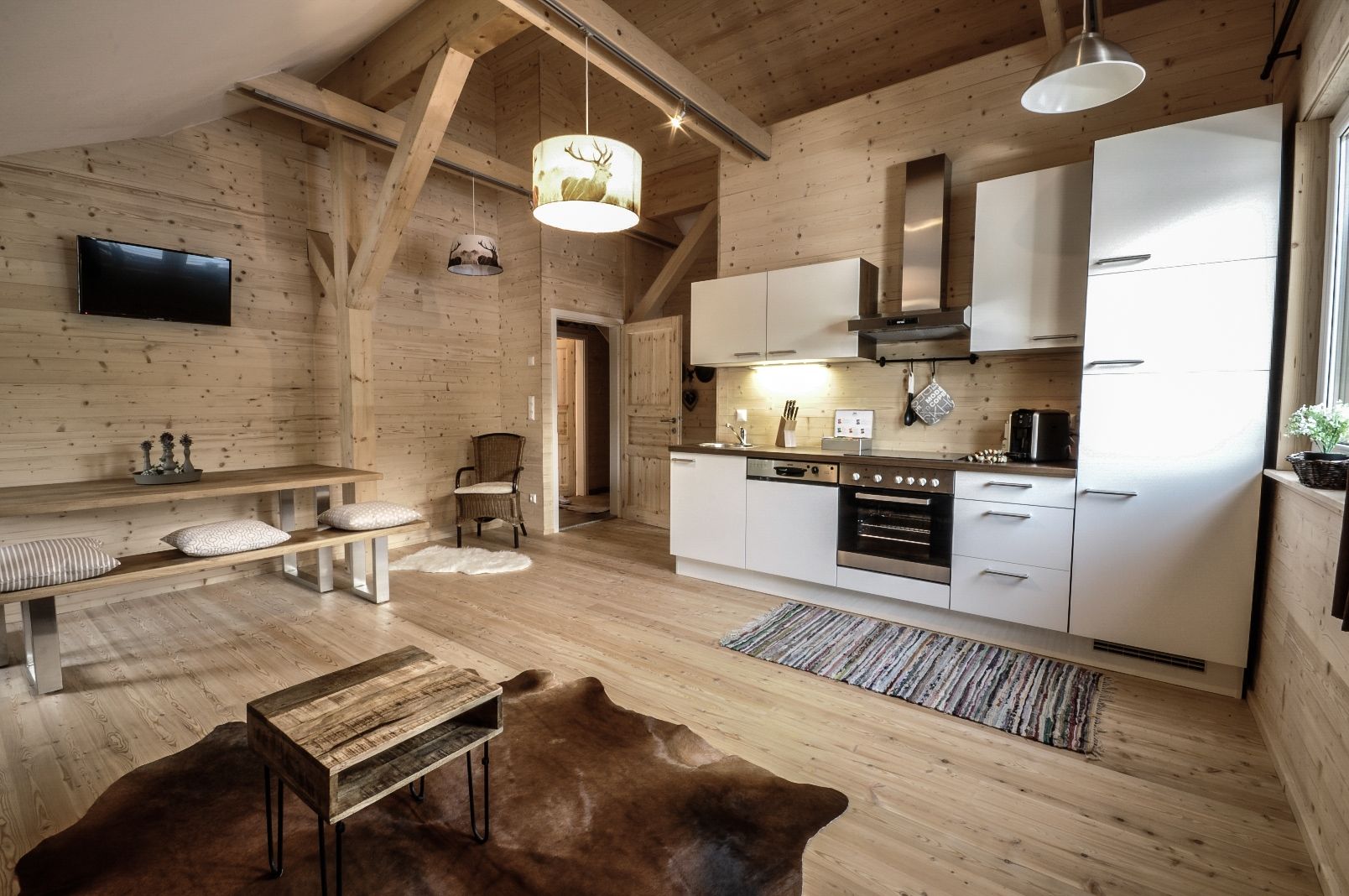 Cozy apartment with wooden walls, modern kitchen, dining table and TV. Rustic style with carpet and wooden furniture.