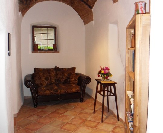 Historic room with terracotta tiles and a two-seater couch in dark brown.