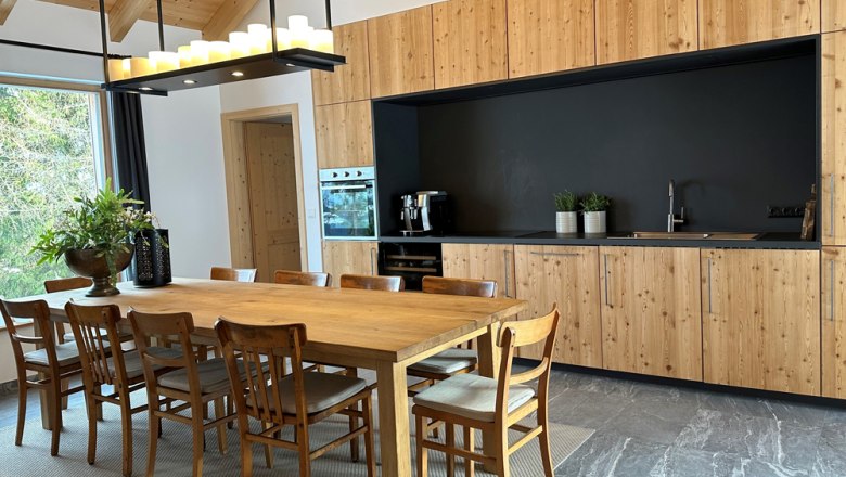 Modern kitchen with wooden furniture and large dining table.