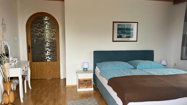 Bedroom with double bed, chest of drawers and wooden door.