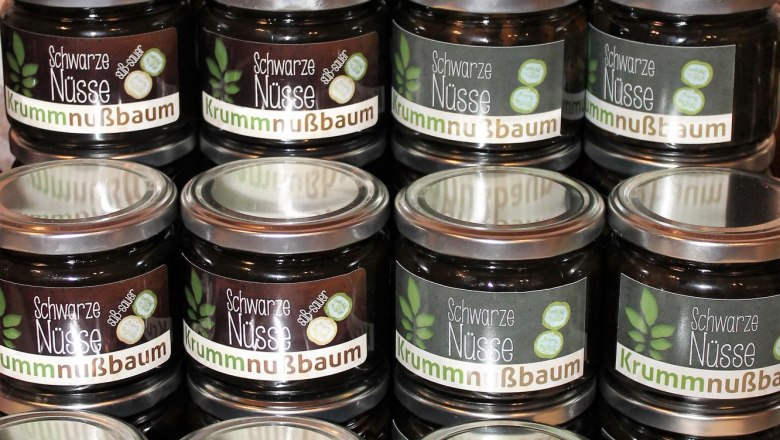 Several jars labeled 'Schwarze Nüsse Krummnußbaum' stacked on a table.